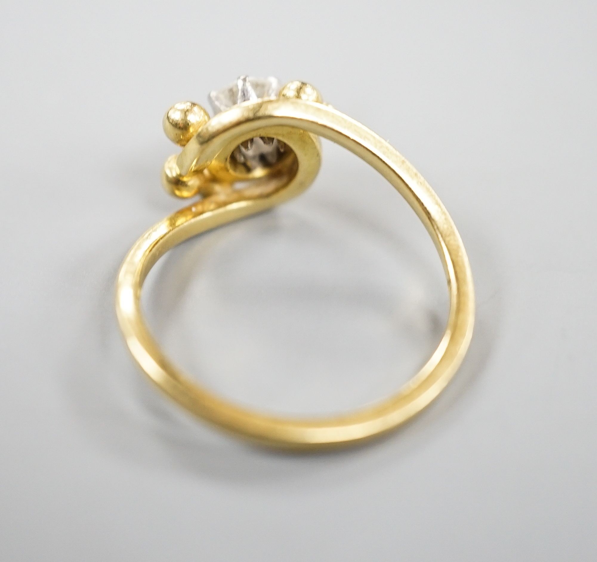A modern 18ct gold and solitaire diamond ring, in crossover setting, size L, gross weight 3.6 grams.